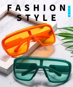 Detail of oversized one-piece cycling sunglasses in vibrant orange and forest green frames