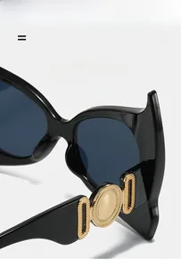 Close-up of black cat-eye sunglasses featuring elegant gold hollowed metal decorations