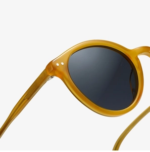 Detail of amber acetate sunglasses frame with polished silver rivets and dark lenses