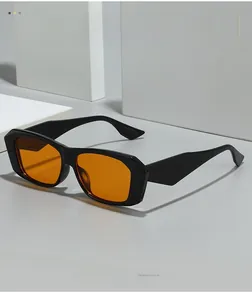 Vue latérale de lunettes de soleil carrées noires avec verres oranges sur fond gris