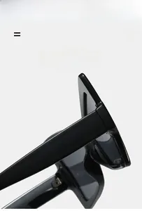 Détail de lunettes de soleil œil-de-chat noires avec monture large et branches épaisses