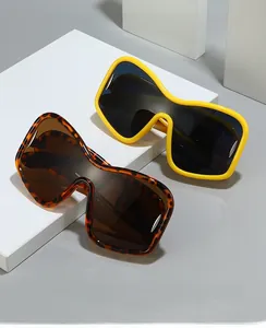 Detail view of yellow and tortoiseshell Y2K oversized wrap sunglasses on a white pedestal