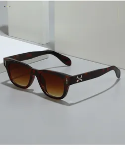 Détail de lunettes de soleil carrées en écaille avec des ornements en croix argentée et verres