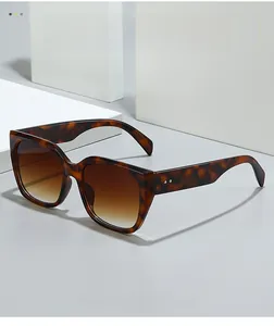 Close-up of tortoiseshell oversized square sunglasses with brown gradient lenses and rivets
