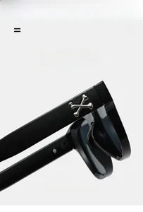 Détail de la branche de lunettes de soleil carrées noires avec os croisés argentés