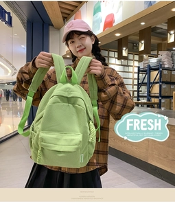 Detail of light green corduroy backpack showing fabric texture and multiple pockets