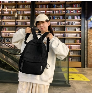 Detail of a minimalist black corduroy backpack with front pocket shown in library setting