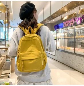 Rear view of a yellow corduroy backpack with sturdy straps in a modern bakery setting