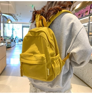 Model wearing mustard yellow corduroy backpack showing large capacity and textured fabric
