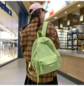 Detail of light green corduroy backpack showing textured fabric and front pocket design