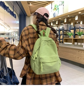 Rear view of a light green corduroy backpack showing vertical texture and zipper details