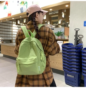 Detail of light green corduroy backpack with zipper pocket shown on person