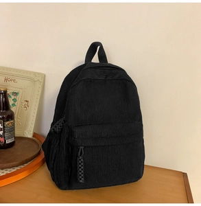 Close-up of black corduroy texture and woven rope zipper pull on a minimalist backpack