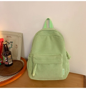 Close-up of light green corduroy backpack showing ribbed texture and zipper detail