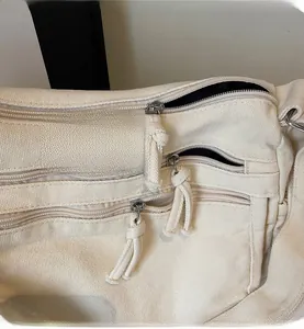 Detail of multi-layer zipper closure on cream canvas tote bag with woven texture