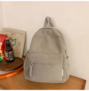 Detailed view of grey corduroy backpack texture with zipper pocket on wooden surface