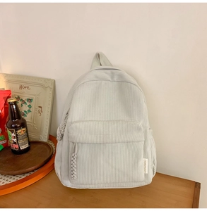 Close-up of beige corduroy backpack texture on wooden table with vintage decor
