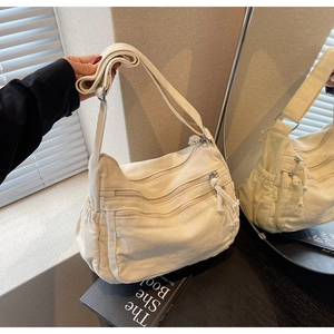 Detail view of off-white canvas tote bag featuring multiple zipper pockets and adjustable strap