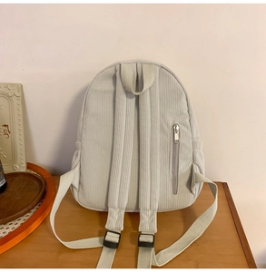 Rear view detail of light grey corduroy backpack showing back vertical metal zipper pocket