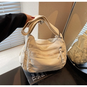 Close-up of cream canvas tote bag showing thick fabric texture and multi-pocket zippers