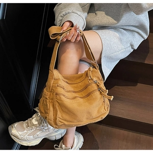 Detail of retro brown canvas tote bag featuring three front zipper pockets and drawstring design