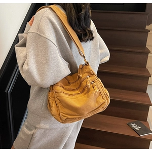 Close-up of yellow canvas tote bag featuring multi-pocket zipper design and wide strap