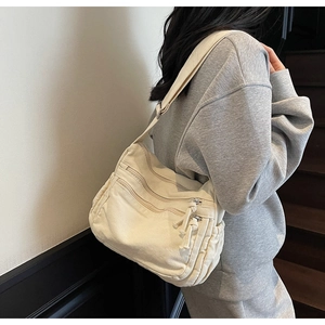 Close-up of cream canvas tote bag featuring three-tier horizontal zipper pockets