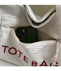 Detail der Cord-Einkaufstasche mit vorderem Reißverschlussfach und roter TOTE BAG Stickerei