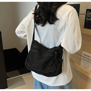 Rear view of minimalist black canvas tote bag with multi-pocket design on model