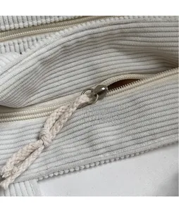 Detail eines silbernen Reißverschlusses mit Kordelzug auf beigem Cordstoff