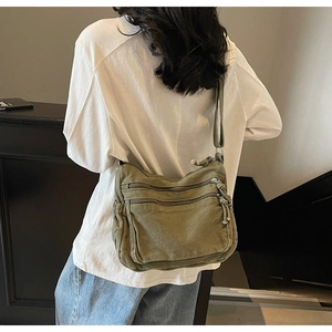 Detailed back view of a versatile olive green canvas crossbody bag with multiple zippers