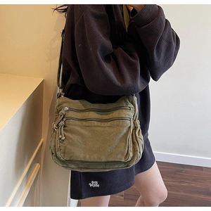 Detail of army green canvas tote bag featuring double front zipper pockets and strap