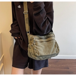 Close-up of army green canvas tote with dual front zipper pockets and wide strap