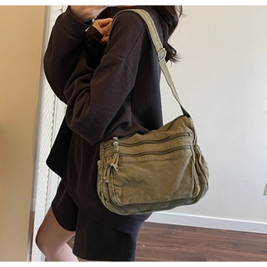 Side view of olive green canvas messenger bag with adjustable strap and multiple zip pockets