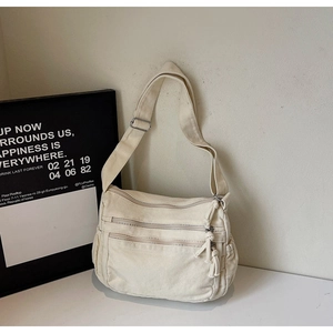 Detailed macro view of the three zipper pockets and canvas texture on a white tote bag
