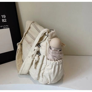 Detail view of canvas tote bag side pocket with compact umbrella storage and zipper compartments