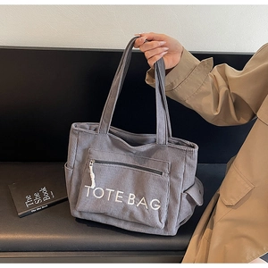 Detail der grauen Cord-Einkaufstasche mit TOTE BAG Stickerei und Reißverschlussfach