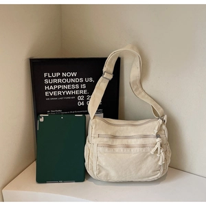 Detail of cream canvas tote bag showing multiple zipper pockets and wide shoulder strap