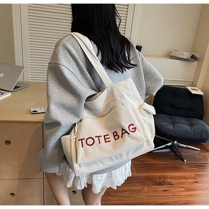 Detailansicht einer weißen Cord-Tasche mit roter Stickerei auf der Schulter getragen