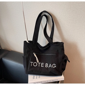 Nahaufnahme der schwarzen Cord-Einkaufstasche mit TOTE BAG Stickerei und Seitentaschen
