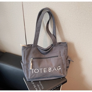Detailansicht der dunkelgrauen Cord-Tasche mit weißer Bestickung und praktischen Seitentaschen