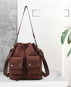 Detail of dark coffee nylon bucket bag showing drawstring closure and double front pockets
