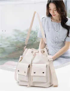 Detail of off-white nylon bucket bag featuring drawstring closure and front flap pockets