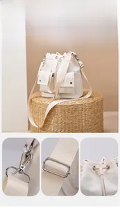Detail view of cream nylon bucket bag with drawstring closure and silver hardware hooks