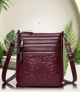 Macro detail of embossed rose pattern on wine red leather handbag with silver zippers