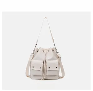 Front view of beige nylon drawstring bucket bag with dual flap pockets and metal hardware