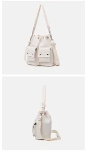 Detail view of cream nylon bucket bag with dual front pockets and drawstring closure