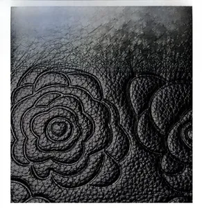 Close-up of black litchi grain faux leather with camellia embossed pattern detail