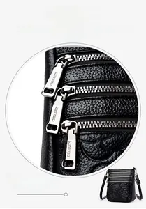 Detail view of the black embossed leather bag showing three metal zipper compartments
