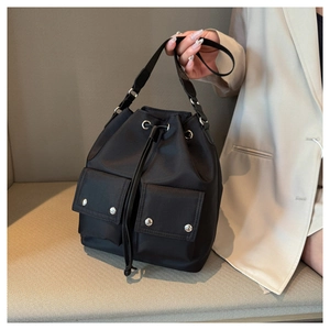 Detail view of black nylon bucket bag featuring drawstring closure and front flap pockets